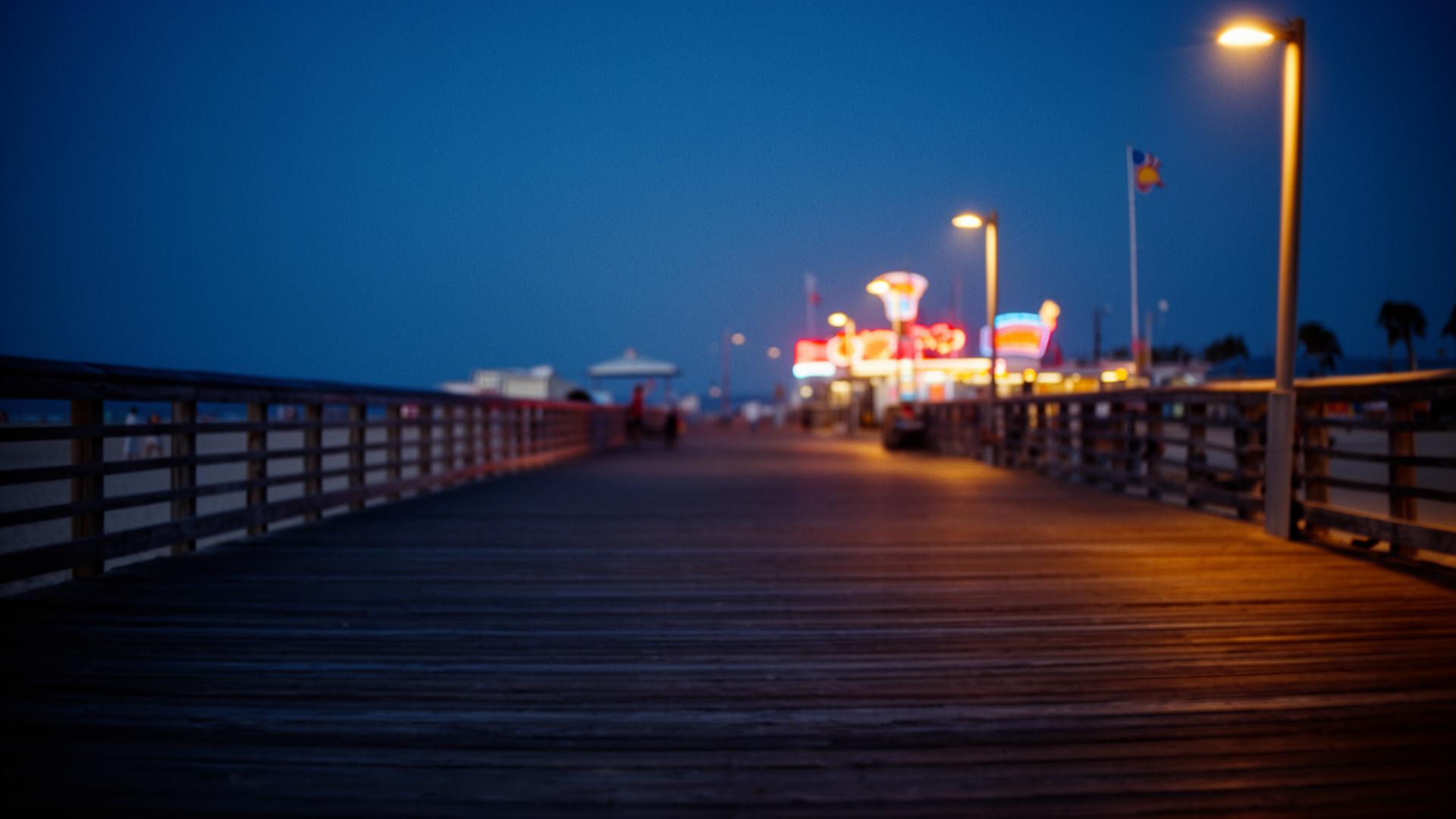 A boardwalk at dusk with distant neon